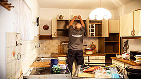 Mann wie er die Küche ausräumt und demontiert.